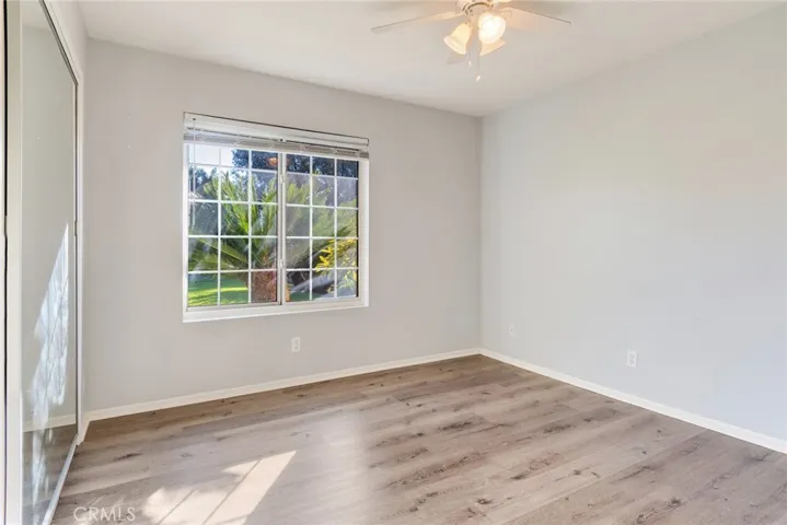 Bedroom #3 features a window looking out into the beautiful front yard with mirrored closet doors.