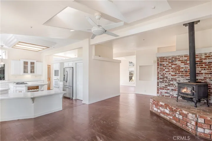 Family room has wood-burning stove and is open to the kitchen and the expansive living room in the background.