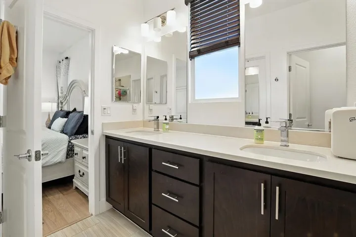 Ensuite bathroom featuring double vanity and light wood-style flooring
