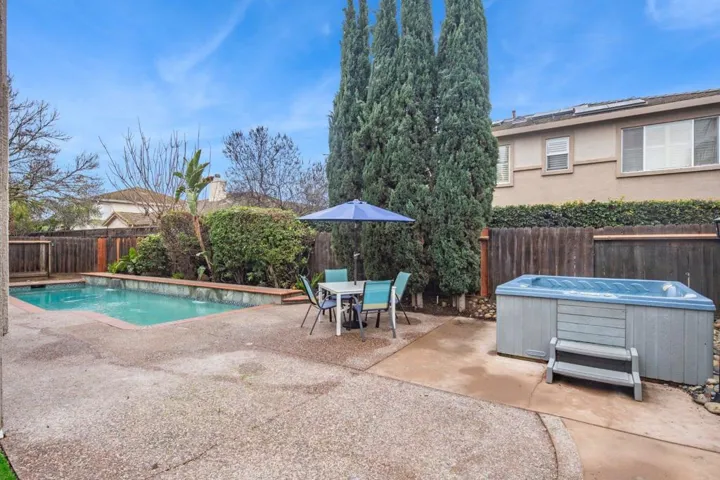 View of pool featuring outdoor dining area, a patio, a fenced backyard, and a hot tub