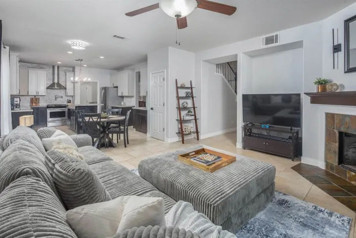 Living room with light tile patterned floors, a ceiling fan, recessed lighting, a tile fireplace, and a chandelier