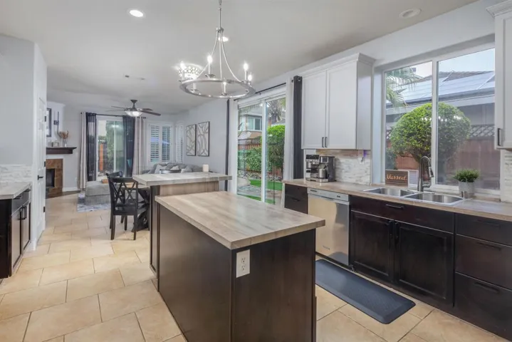 Kitchen featuring backsplash, a kitchen island, butcher block counters, a chandelier, and dishwasher