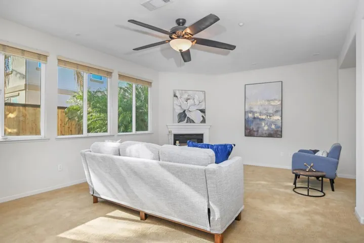 Living room featuring a fireplace, light carpet, and a ceiling fan