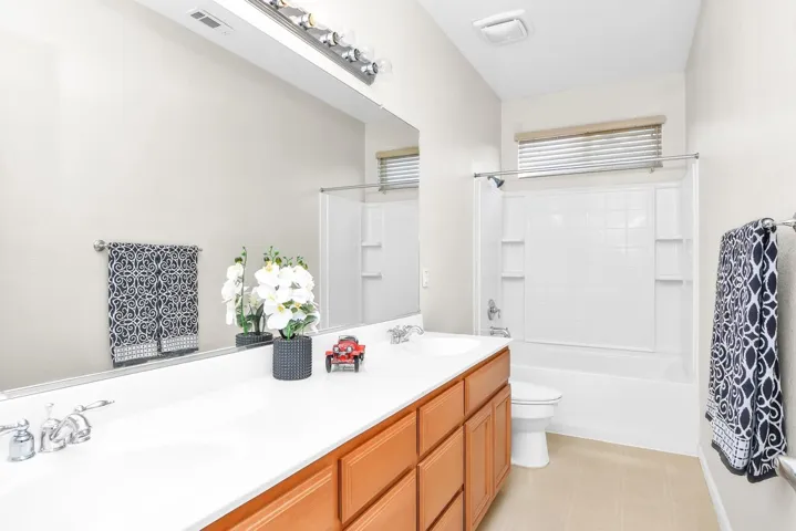 Full bathroom with double vanity and washtub / shower combination