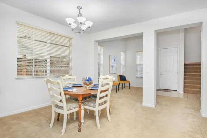 Dining space featuring light carpet, a chandelier, and stairs