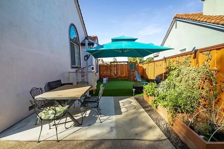 Fenced backyard with a patio area, a playground, and outdoor dining space