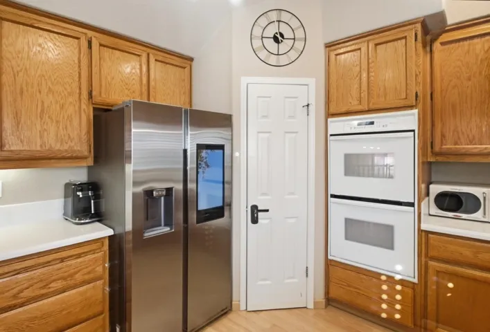 Kitchen with white appliances, light countertops, light wood-style flooring, and brown cabinets