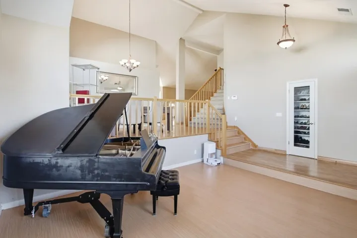 Living area featuring high vaulted ceiling, stairs, wood finished floors, and a chandelier