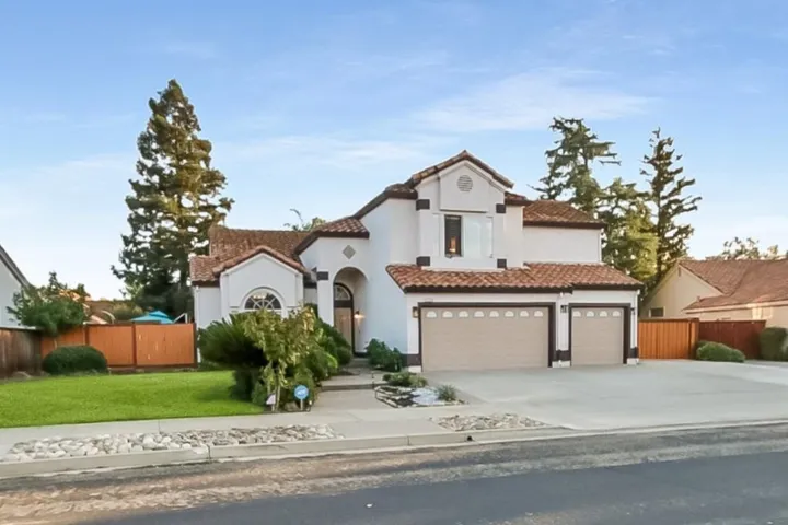 Mediterranean / spanish home with driveway, a tile roof, a garage, and stucco siding