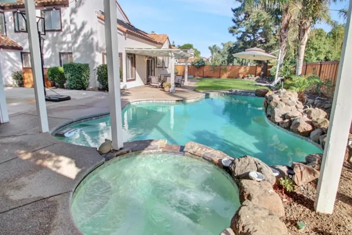 View of swimming pool featuring a pool with connected hot tub, a pergola, a patio area, and a fenced backyard