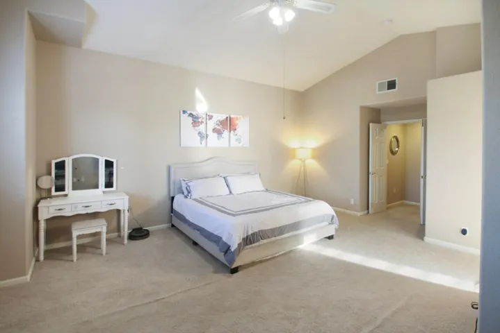 Bedroom with vaulted ceiling, carpet floors, and a ceiling fan