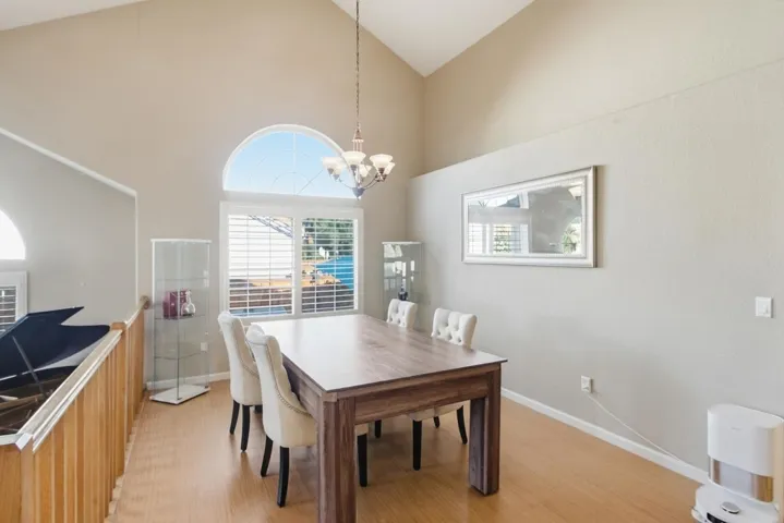 Dining space featuring light wood finished floors, a chandelier, and high vaulted ceiling