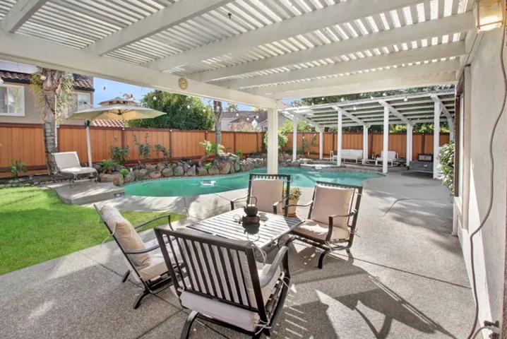 Fenced backyard featuring a patio, a pergola, a pool with connected hot tub, and outdoor dining area