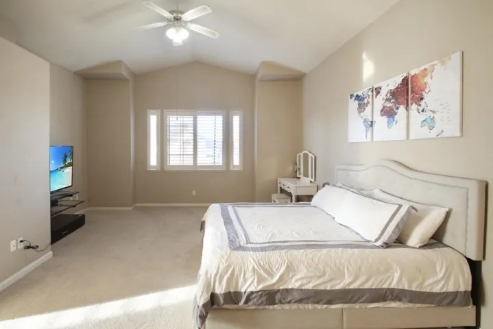 Carpeted bedroom with lofted ceiling and ceiling fan