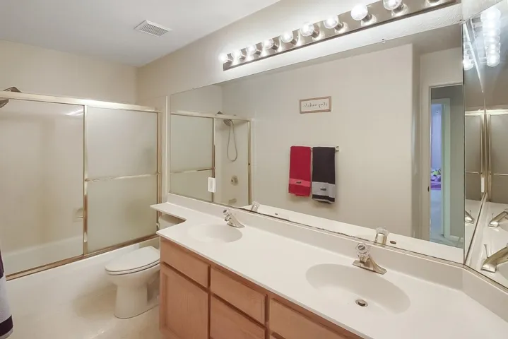 Bathroom featuring double vanity and combined bath / shower with glass door