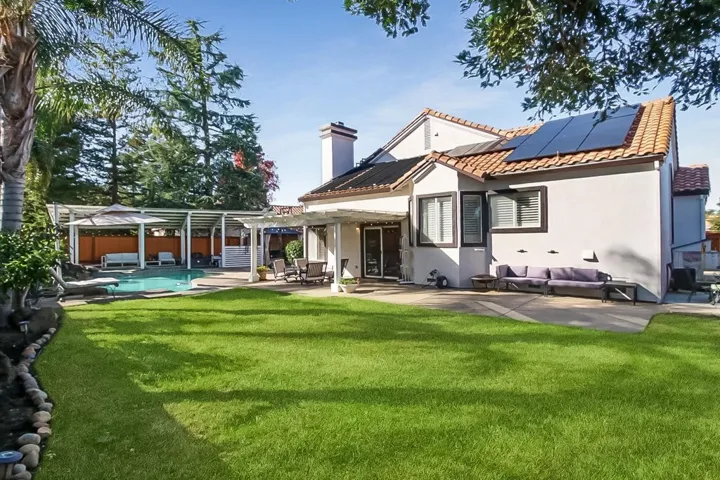Back of house with a patio, roof mounted solar panels, a gazebo, stucco siding, and an outdoor hangout area