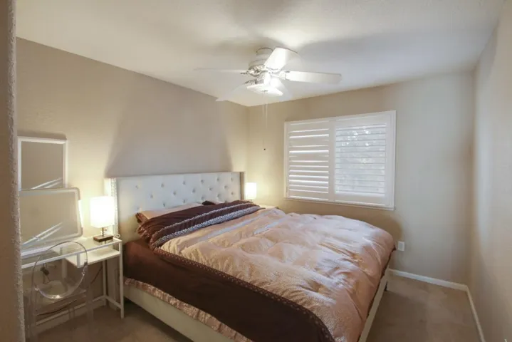 Carpeted bedroom with a ceiling fan and baseboards