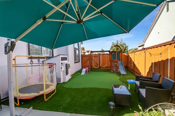 View of play area with a trampoline and a fenced backyard