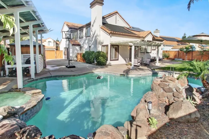 View of swimming pool with a fenced backyard, a patio area, a pergola, a pool with connected hot tub, and an outbuilding