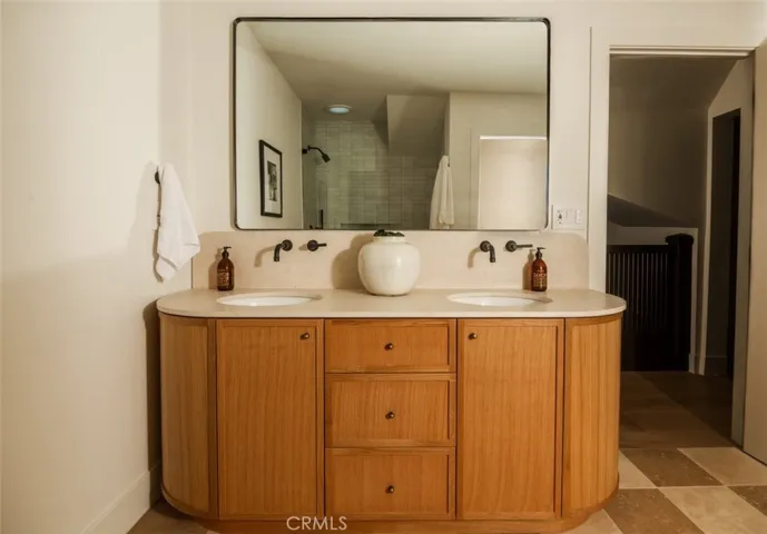 Upstairs hall bath features custom curved millwork, limestone countertops, dual sinks with wall mounted faucets.