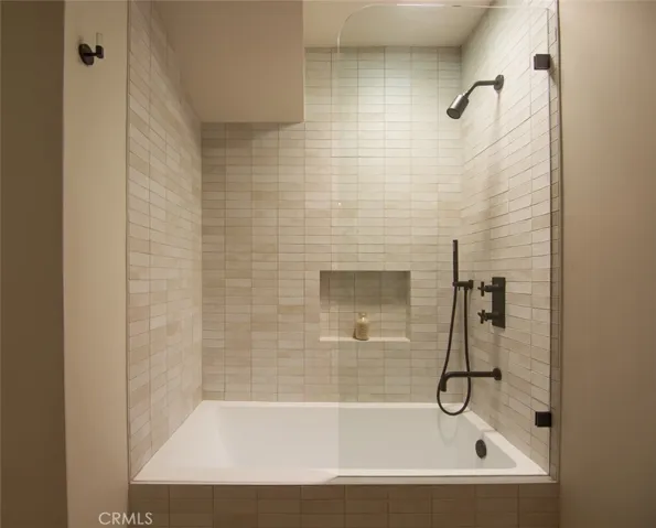 Tub shower features hand made subway tiles, and three feature thermostatic shower set including handshower for added convenience.