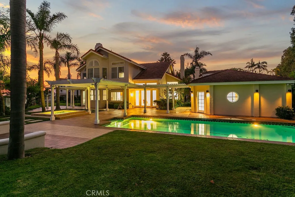 Main house, pool house, pool and spa from a back lawn.