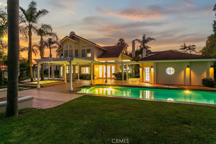 Main house, pool house, pool and spa from a back lawn.
