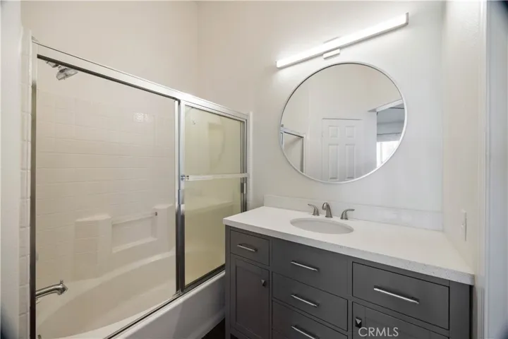 Remodeled primary bathroom with shower in tub, new vanity, mirror and light fixture.