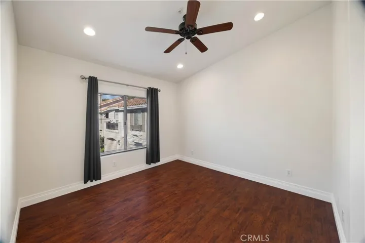 Primary bedroom with hardwood floors, ceiling fan, and recessed lights.