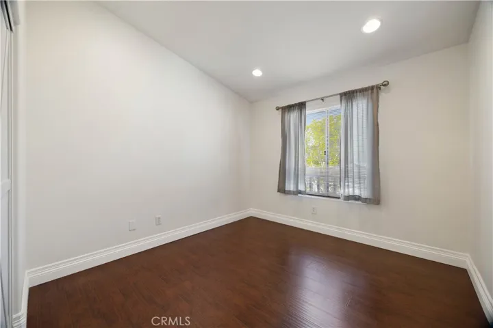 Secondary bedroom with hardwood floors and recessed lights.