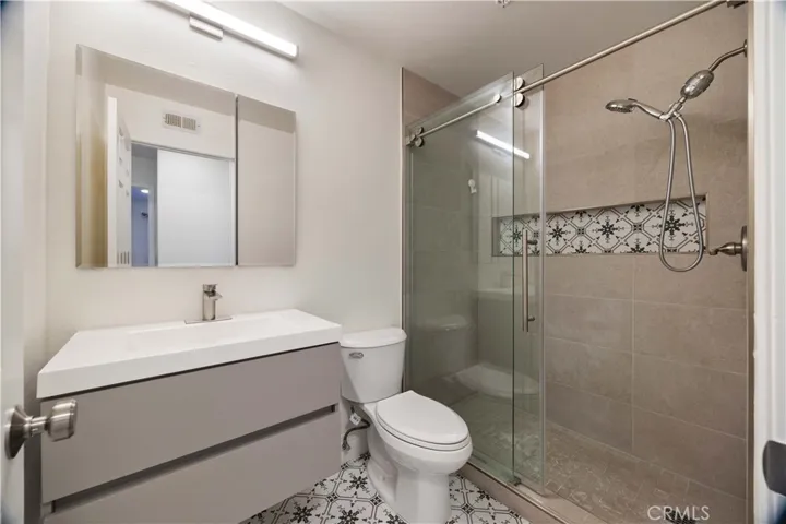 Remodeled hallway bathroom with walk-in shower, mosaic tile floors, brushed nickel fixtures, new vanity and light.