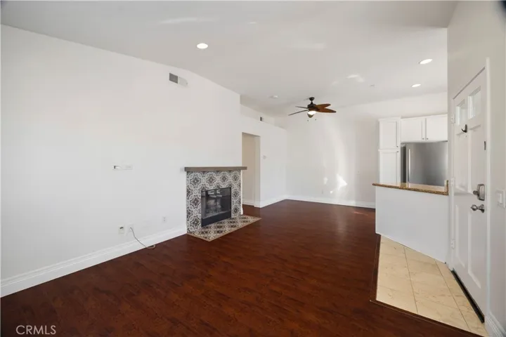 Living room has high ceilings, recessed lights, mosaic tiled fireplace and hardwood floors.