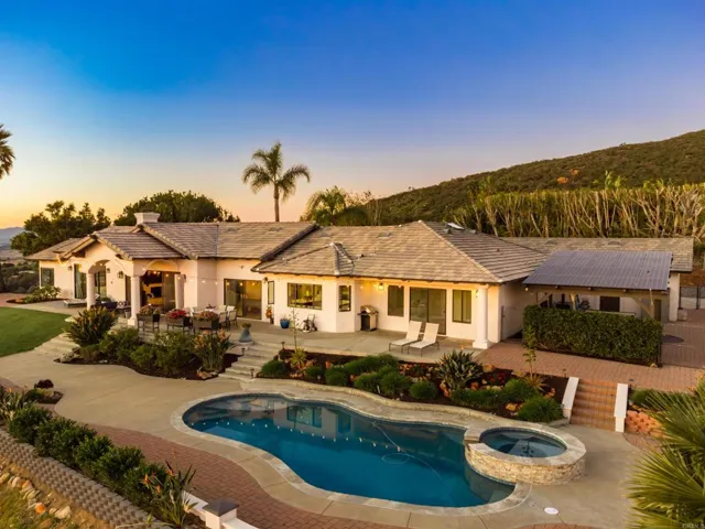 Resort-style pool and spa with lush landscaping, hillside backdrop, and sunset views.