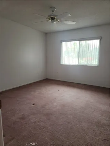 Front Guest Bedroom with ceiling fan and large window looking out onto the courtyard