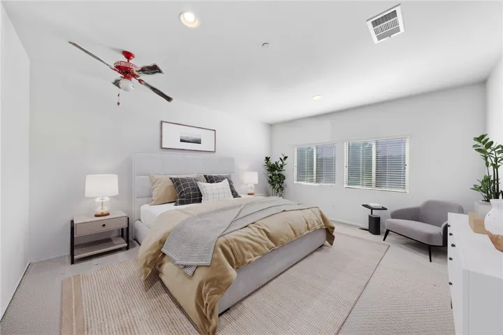 Spacious primary bedroom with abundant natural light, plush carpeting, and room for a sitting area