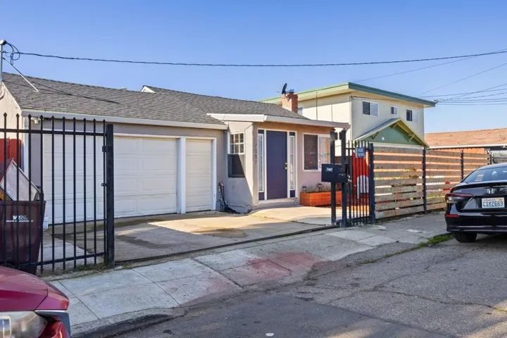 View of front facade with a gate, roof with shingles, a garage, and stucco siding