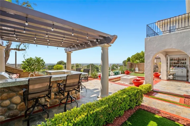 The backyard is a sanctuary featuring tranquil water features, outdoor kitchen with built-in BBQ, and multiple spaces designed for entertaining and relaxation.