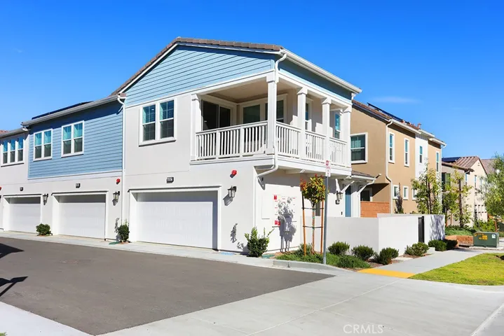 Front exterior view of a contemporary multi-level townhome with attached garage and private balcony.