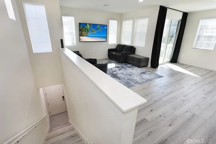 Living room angle highlighting balcony access, multiple windows, and neutral flooring.
