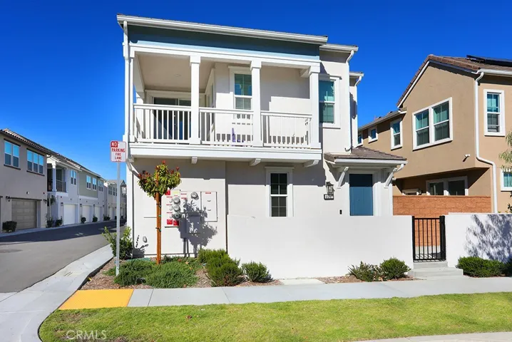 Side exterior view of townhome showcasing architectural details, balcony above, and landscaped surroundings.