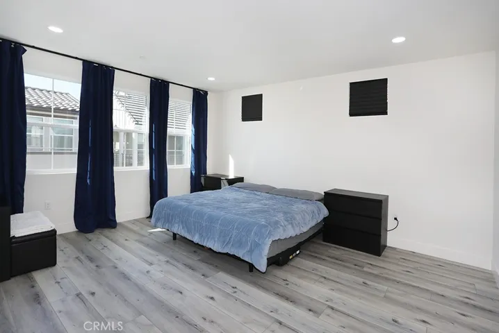 Spacious primary bedroom with recessed lighting, neutral flooring, and multiple windows.