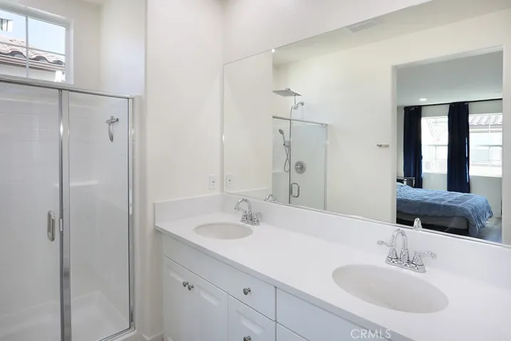 Primary bathroom featuring dual sink vanity, quartz countertops, and large wall mirror.