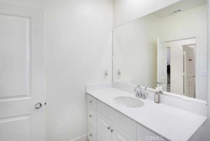 Clean and modern bathroom with white vanity, quartz countertop, and large wall mirror.