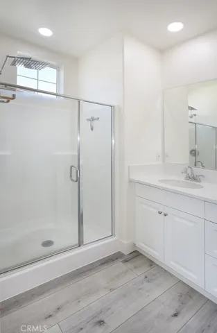 Alternate view of primary bathroom highlighting glass-enclosed shower and recessed lighting.