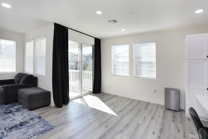 : Open living room with recessed lighting, large windows, and sliding door access to balcony.