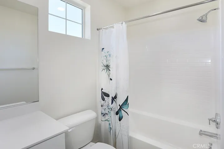 Bathroom with tub-and-shower combination, tile surround, and window for natural light.