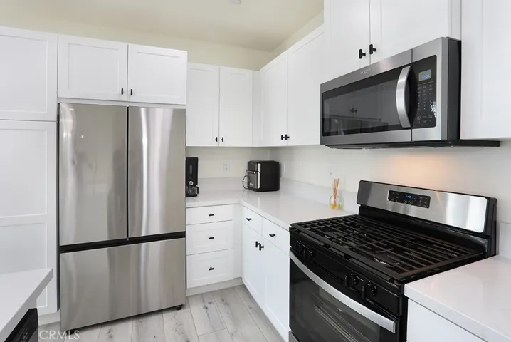 : Kitchen view showcasing stainless steel refrigerator, corner counter space, and ample storage