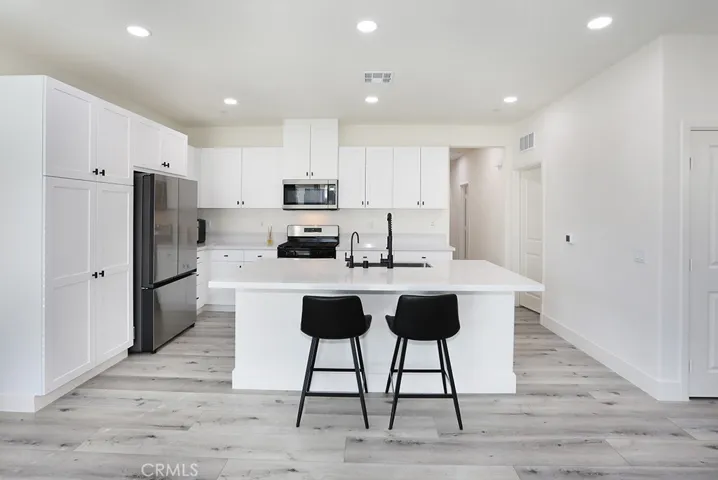 Wide-angle view of kitchen highlighting center island, recessed lighting, and open-concept design.