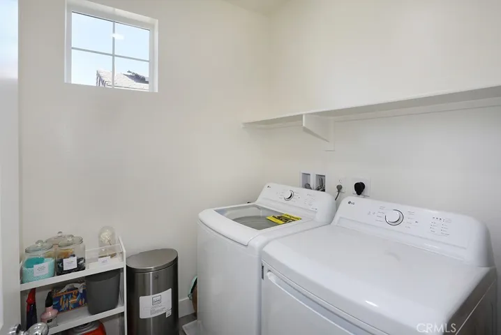 Dedicated laundry room with washer and dryer hookups, overhead shelving, and window for natural light.