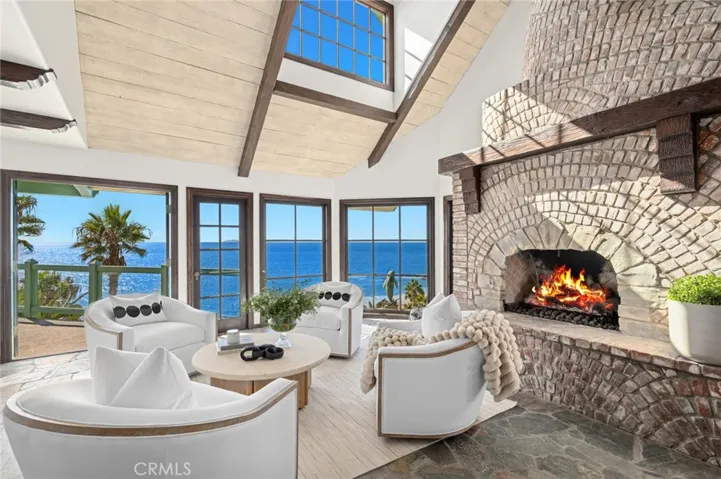 Inside, stone floors, a sculptural floating staircase, and soaring beamed ceilings frame endless ocean vistas.
